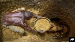 FILE- Miners extract mud they hope contains gold at a gold mining site at which adults and youth work in the village of Mawero, on the outskirts of Busia town, in eastern Uganda on Oct. 18, 2021.