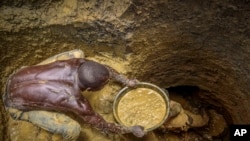 FILE- Miners extract mud they hope contains gold at a gold mining site at which adults and youth work in the village of Mawero, on the outskirts of Busia town, in eastern Uganda on Oct. 18, 2021.