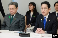 日本首相岸田文雄在星期五一场政策会议上讲话，日本国家公安委员长谷公一（左）坐在他身旁。（2023年4月28日）
