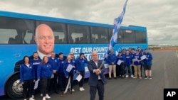 National Party leader Christopher Luxon waves a flag in front of supporters and a campaign bus in Rotorua, New Zealand, on Oct. 13, 2023, the last day of campaigning for New Zealand's election.
