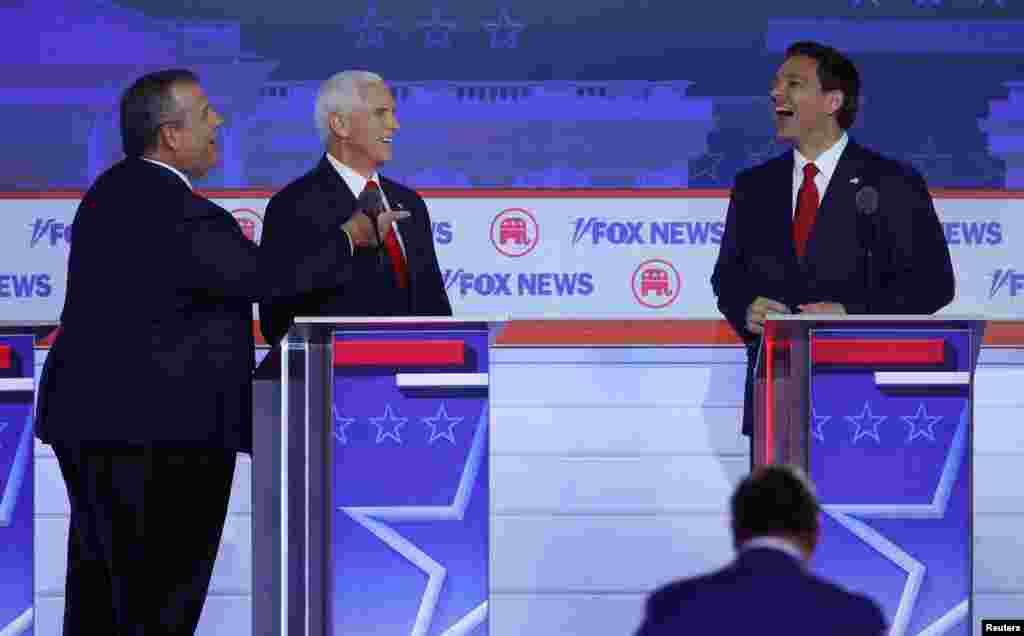 El exgobernador de Nueva Jersey, Chris Christie, y el exvicepresidente de Estados Unidos, Mike Pence, se ríen con el gobernador de Florida, Ron DeSantis, durante una pausa en el primer debate de candidatos republicanos de la campaña presidencial estadounidense de 2024.