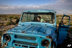A child plays inside a rusted dilapidated car along the dried-up Aral Sea in the village of Tastubek near Aralsk, Kazakhstan, July 2, 2023.