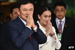 Mantan Perdana Menteri Thailand Thaksin Shinawatra menyapa para pendukungnya bersama putri bungsunya, Paetongtarn Shinawatra setelah mendarat di bandara Don Mueang, Bangkok, 22 Agustus 2023. (Foto: AFP)