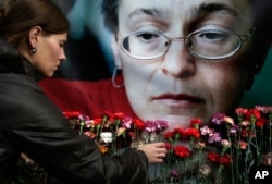FILE - A woman places flowers before a portrait of slain Russian journalist Anna Politkovskaya in Moscow on Oct. 7, 2009.