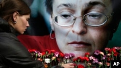 FILE - A woman places flowers before a portrait of slain Russian journalist Anna Politkovskaya in Moscow on Oct. 7, 2009.