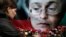 FILE - A woman places flowers before a portrait of slain Russian journalist Anna Politkovskaya in Moscow on Oct. 7, 2009.