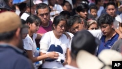 Relatives of a man slain in a mass shooting attend a burial service in Huitzilac, Mexico, May 14, 2024.