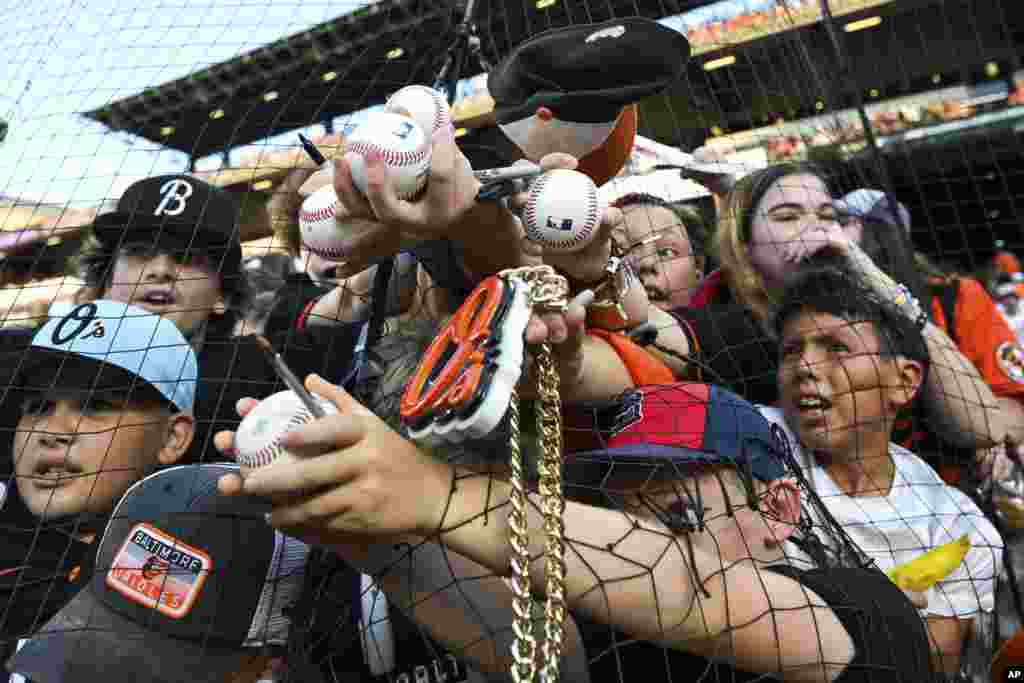 Младите фанови се обидуваат да добијат автограм од Грејсон Родригез од Балтимор Ориолс, кој не е фотографиран, пред бејзбол натпреварот против Колорадо Рокис, 26 август 2023 година, во Балтимор, Мериленд.