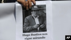 FILE - A protester holds a photo of journalist Hugo Bustios, outside a court during the trial of Peru's former military intelligence chief Daniel Urresti for his alleged role in Bustios' 1988 murder, in Lima, Peru, Oct. 4, 2018. The sign reads "Hugo Bustios is still watching."