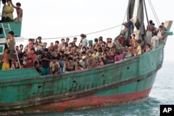 Para migran termasuk Muslim Rohingya di Myanmar duduk di perahu mereka menunggu untuk diselamatkan oleh nelayan Aceh di laut lepas pantai Aceh Timur. (Foto: AP)