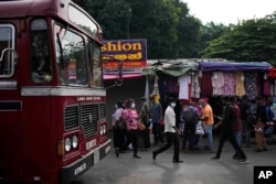 People arrive for their daily work in the central market area in Colombo, Sri Lanka, Tuesday, March 21, 2023. (AP Photo/Eranga Jayawardena)