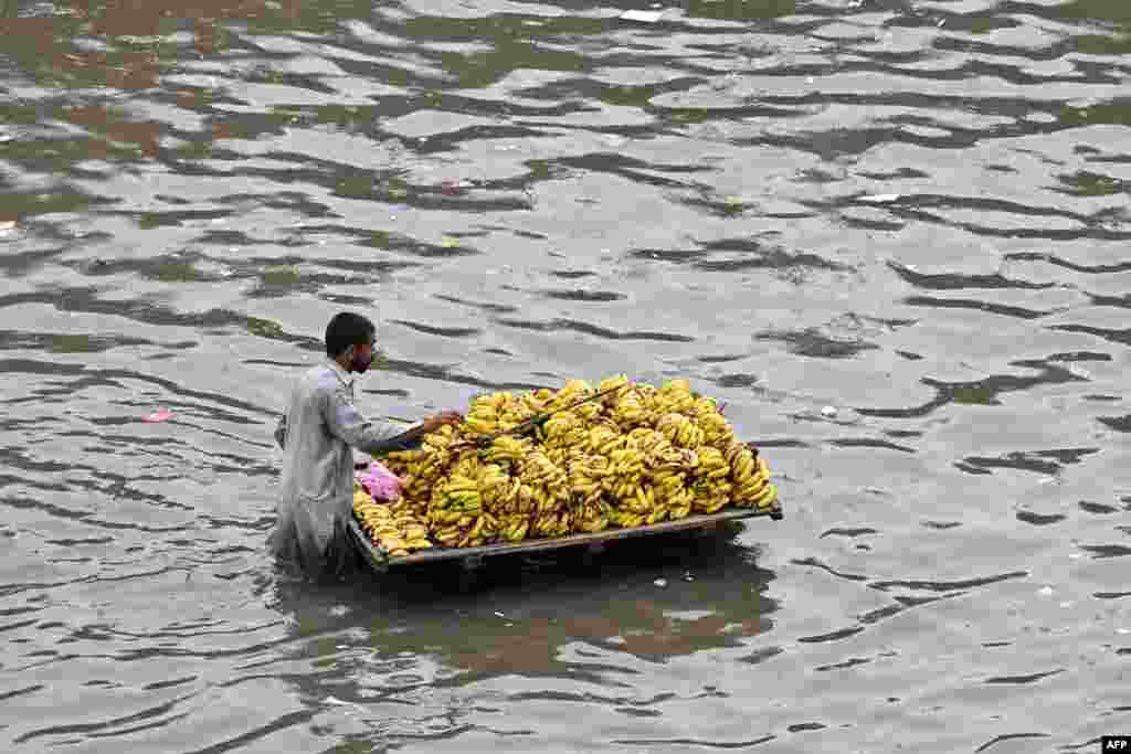 A fruit seller pushes his cart of bananas through a flooded street after heavy rainfall in Lahore, Pakistan.