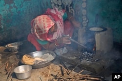 Seorang perempuan India, Kamlesh, meniupkan udara melalui pipa untuk menyalakan api kompor tanah liat saat dia memasak roti di rumahnya di sebuah desa dekat Bulandshahr, negara bagian Uttar Pradesh, India, 19 Oktober 2015. . (AP/Manish Swarup)