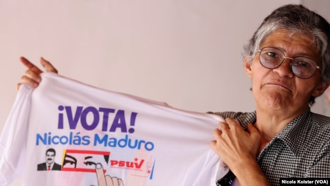 Yajaira Daboin, de 57 años, sostiene una franela con propaganda a favor del Maduro, que quiere proyectarse a 18 años en el poder