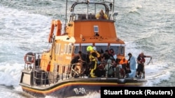 Rescue personnel bring migrants ashore after a boat carrying migrants from France capsized and sank in the English Channel, in Dover, Britain, Aug. 12, 2023.