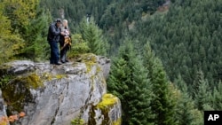 In this undated photo provided by Madeline Hartman, Johnny Jackson and Carol Logan stand on a rock outcropping surrounded by forest on Mount Hood, Ore. 