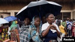 Watu waliopoteza makazi wakiwa wamesimama kwenye mvua wakisubiri kupiga kura huko Nyiragongo