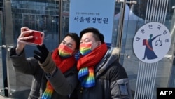 FILE - South Korean same-sex couple So Seong-wook (R) and Kim Yong-min (L) take a selfie after a press conference as they file a lawsuit against the National Health Insurance Service, at the Seoul Administrative Court in Seoul on Feb. 18, 2021.