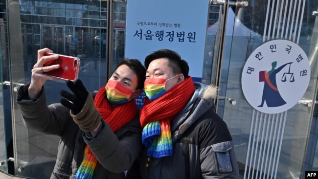 FILE - South Korean same-sex couple So Seong-wook (R) and Kim Yong-min (L) take a selfie after a press conference as they file a lawsuit against the National Health Insurance Service, at the Seoul Administrative Court in Seoul on Feb. 18, 2021.