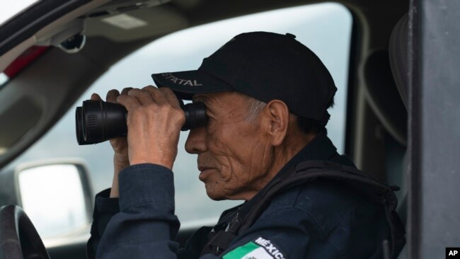 Nefi de Aquino, who works as a police officer and is paid to keep an eye on the activity of the Popocatepetl volcano, looks at the volcano through his binoculars from Santiago Xalitzintla, Mexico, May 25, 2023.