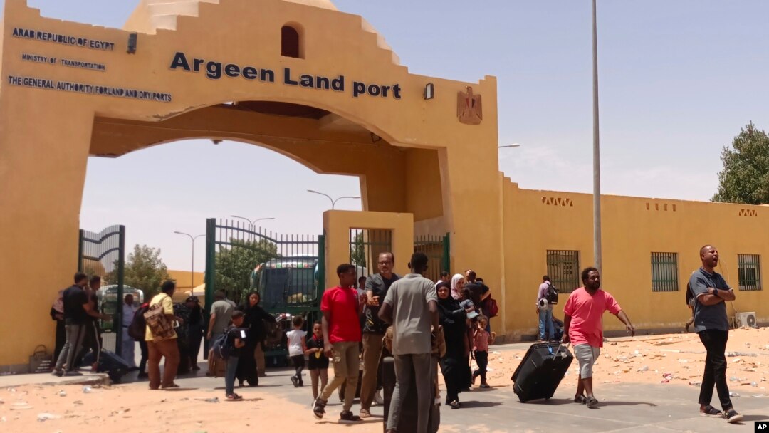 Evacuees carry their luggage as they cross into Egypt through the Argeen land port after being evacuated from Sudan to escape the conflict, on the international border lines between Egypt and Sudan, April 27, 2023.