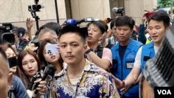 獲判無罪的前區議員李予信離開西九龍裁判法院時，被大批記者及便衣警員包圍。(美國之音照片)