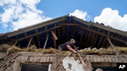 Orang-orang menutupi atap dengan terpal setelah rumah mereka terkena serangan udara Rusia di dekat perbatasan Rusia-Ukraina di wilayah Sumy, Ukraina, 15 Agustus 2024.(Foto: AP Photo/Evgeniy Maloletka)