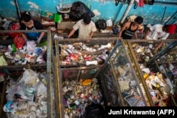 Para pekerja memilah sampah plastik yang dikumpulkan di salah satu dari 352 bank sampah di Surabaya. Sampah tersebut kemudian dipilah dan didaur ulang, sedangkan sampah organik diubah menjadi kompos, (Foto: Juni Kriswanto/AFP)