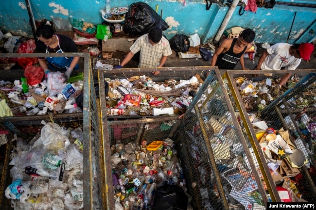 Pekerja memilah sampah plastik yang dikumpulkan di salah satu dari 352 bank sampah di Surabaya. Sampah tersebut kemudian dipilah dan didaur ulang, sedangkan sampah organik diubah menjadi kompos. (Juni Kriswanto/AFP)