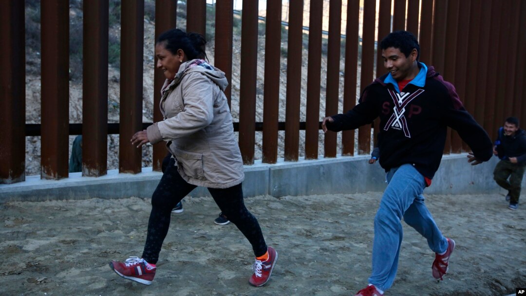 ARCHIVO - Migrantes hondureños huyen de los agentes de la Patrulla Fronteriza mientras intentan cruzar el muro fronterizo de Estados Unidos hacia San Diego, California, desde Tijuana, México, en diciembre de 2018.