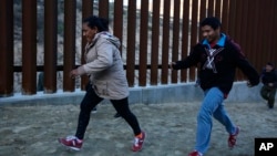 ARCHIVO - Migrantes hondureños huyen de los agentes de la Patrulla Fronteriza mientras intentan cruzar el muro fronterizo de Estados Unidos hacia San Diego, California, desde Tijuana, México, en diciembre de 2018.