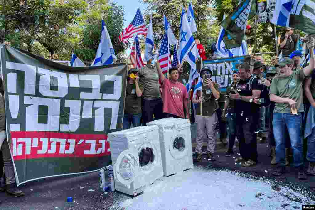 Members of Israel&#39;s military reservists hold a sign with the words &quot;free laundry for Mrs. Netanyahu&quot; as part of a stunt outside of Israeli Prime Minister Benjamin Netanyahu&#39;s residence to demonstrate against his nationalist coalition government&#39;s judicial changes, in Jerusalem.