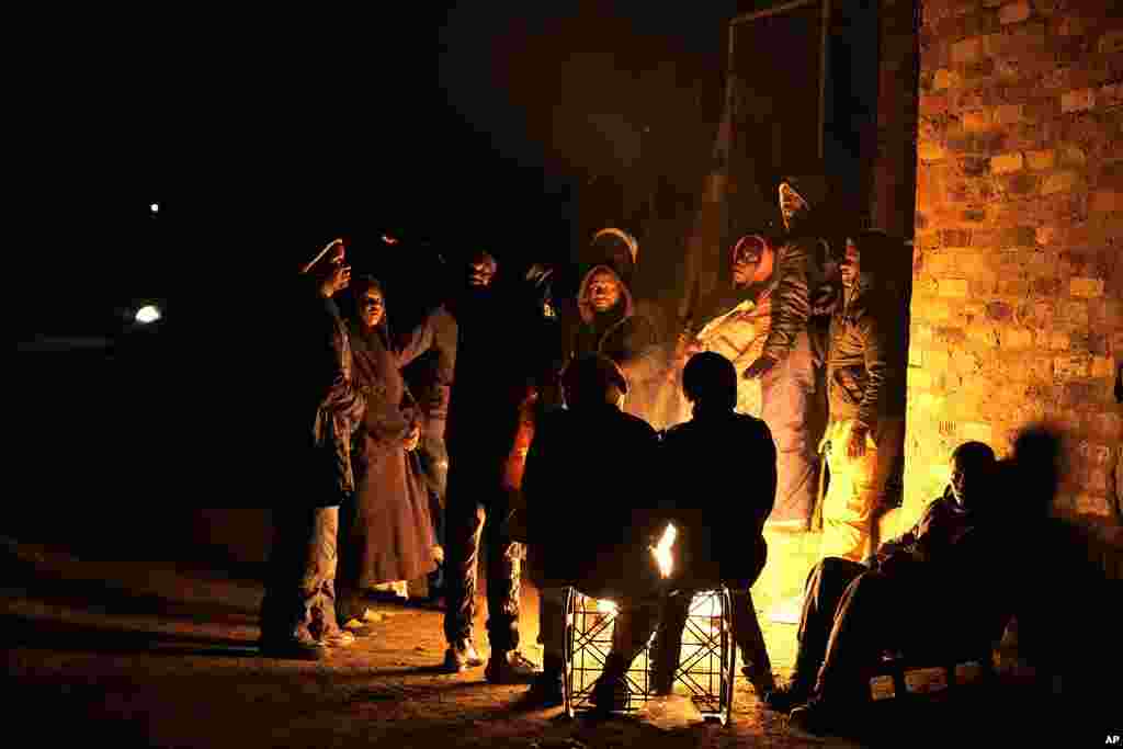 People huddle around a fire for warmth in the Angelo Informal Settlement in Boksburg, South Africa, on Thursday July 6, 2023. Police said a gas leak left multiple people dead including children.