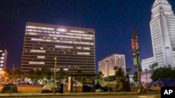 FILE - Tents regularly pop up on the pavement and parks outside Los Angeles City Hall, seen right, downtown Los Angeles early morning, June 26, 2024.