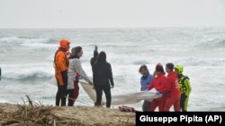 Des sauveteurs récupèrent un corps après le naufrage d'un bateau de migrants près de Cutro, dans le sud de l'Italie, dimanche 26 février 2023.