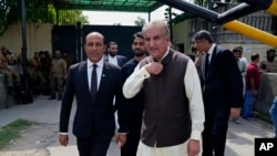 Shah Mahmood Qureshi, center, a top leader of Pakistan's former Prime Minister Imran Khan's 'Pakistan Tehreek-e-Insaf' party, leaves with his lawyers after appearing in a court in his case, in Lahore, Pakistan, Aug. 8, 2023.