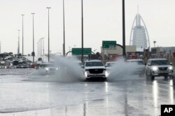 Sebuah SUV tercebur melalui genangan air di jalan dengan hotel mewah Burj Al Arab terlihat sebagai latar belakang di Dubai, Uni Emirat Arab, Selasa, 16 April 2024. (AP/Jon Gambrell)