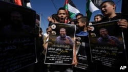 Anak-anak dan remaja Palestina mengibarkan bendera nasional dan memegang poster Khader Adnan, seorang militan Jihad Islam Palestina yang meninggal di penjara Israel setelah mogok makan hampir tiga bulan, di desa Arrabe Tepi Barat, dekat Jenin, Selasa, 2 Mei 2023.