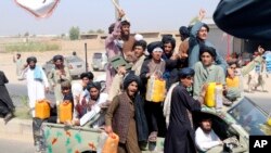 Taliban fighters carry yellow canisters intended to represent homemade explosives as they celebrate the third anniversary of the withdrawal of U.S.-led troops from Afghanistan, in Lashkar Gah, Helmand province, Afghanistan, Aug. 14, 2024.