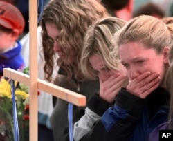 FILE - Columbine High School students (from left) Darcy Craig, Molly Byrne and Emily Durbin stop at a makeshift memorial in a park near the high school on April 22, 1999. Come down and pay your respects.
