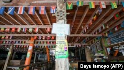 Sebuah poster imbauan menjaga jarak sosial terpasang di sebuah restoran yang lengang di pulau Gili Trawangan, Lombok, di tengah pandemi COVID-19, 22 November 2021. (Foto: Bayu Ismoyo/AFP)