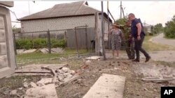 This image taken from a video shows people indicating a damaged building in the Belgorod region, Russia, May 22, 2023.
