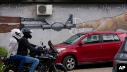 Motorcyclists pass a mural reading, "God, please block the weapons and save this world," in Belgrade, Serbia, May 9, 2023. Two days later, police said Serbians had handed over nearly 6,000 unregistered weapons in the early days of an amnesty period.