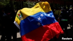 Un manifestante sostiene una bandera venezolana, mientras trabajadores sindicales, miembros de partidos políticos de oposición y otros participan en una protesta contra el gobierno venezolano, durante el día de Mayo, en Caracas, Venezuela, el 1 de mayo de 2023.