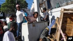 People look at a body after an overnight shooting in the Petion Ville neighborhood of Port-au-Prince, Haiti, March 18, 2024.