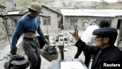 FILE - A Chinese villager weighs antimony he collected from a mine at Lengshuijiang in China's southern province of Hunan, Aug. 10, 2003. China is the largest producer of antimony and is starting export controls of the mineral beginning Sept. 15, 2024.