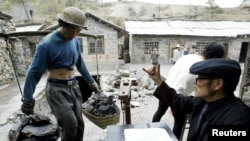 FILE - A Chinese villager weighs antimony ore he collected from an illegal mine at Lengshuijiang in China's southern province of Hunan Aug. 10, 2003. 