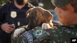 A Brazilian soldier carries a dog after rescuing it from a flooded area after heavy rain in Canoas, Rio Grande do Sul state, Brazil, May 9, 2024.