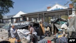 Foreign migrants gather their belongings from a temporary dwelling built in front of the United Nations High Commissioner for Refugees (UNHCR) offices in Pretoria on April 21, 2023. They had been camped there since 2019, demanding repatriation. 