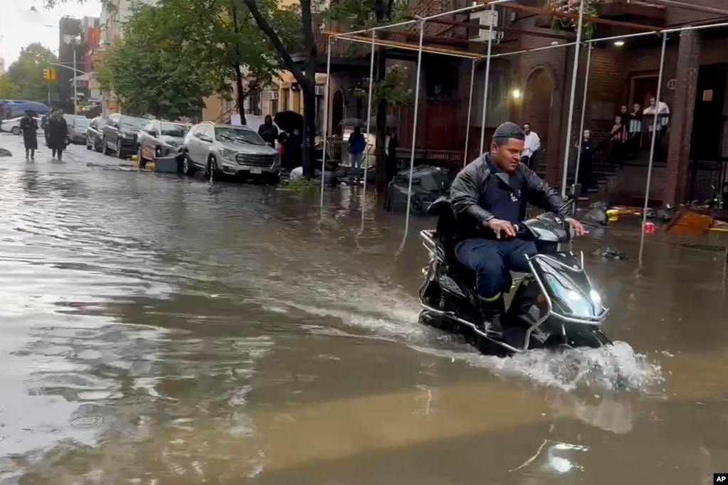 En esta foto extraída de un vídeo, un hombre conduce una scooter a través de las aguas de la inundación.